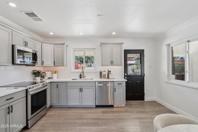 7049 E Latham St, Scottsdale, AZ 85257 - kitchen featuring appliances with stainless steel finishes, a sink, gray cabinets, light wood-type flooring, and crown molding