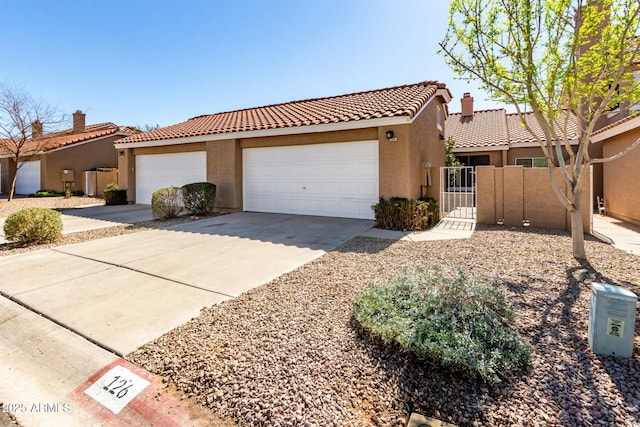 view of front facade featuring concrete driveway, a tiled roof, a gate, fence, and stucco siding