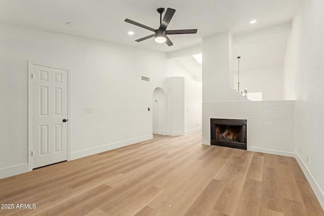 unfurnished living room with lofted ceiling, visible vents, a fireplace, and light wood-style flooring