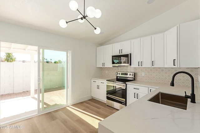 kitchen with lofted ceiling, a sink, light wood-style floors, stainless steel electric range, and tasteful backsplash