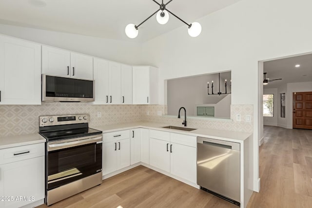 kitchen featuring white cabinets, appliances with stainless steel finishes, light countertops, light wood-style floors, and a sink