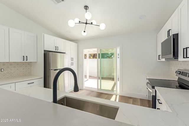 kitchen featuring appliances with stainless steel finishes, white cabinets, a sink, and tasteful backsplash