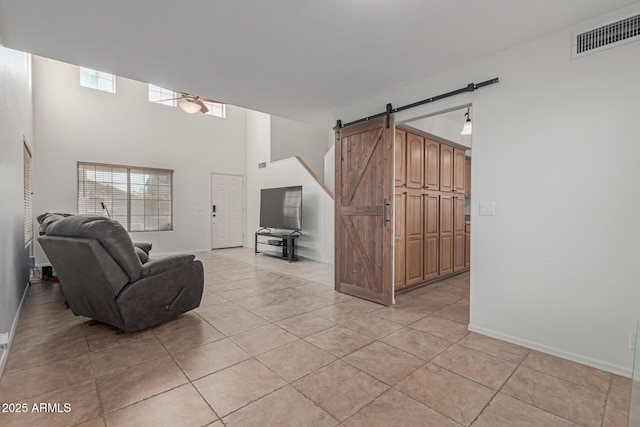 living room featuring light tile patterned floors, a barn door, and a high ceiling