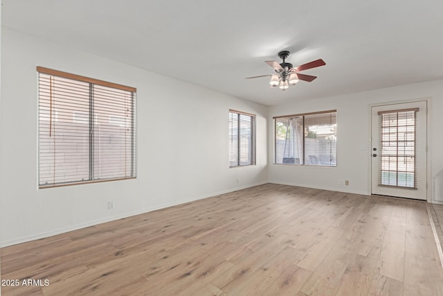 empty room with a wealth of natural light, ceiling fan, and light wood-type flooring