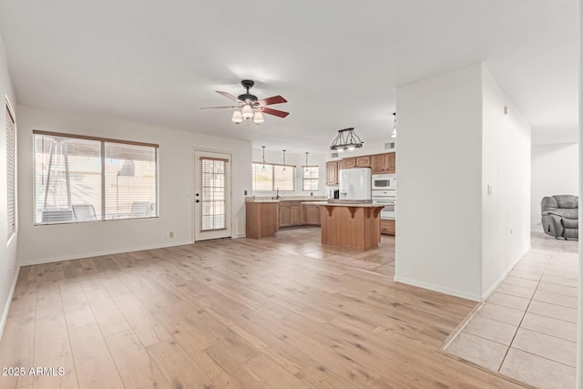 unfurnished living room with ceiling fan and light wood-type flooring