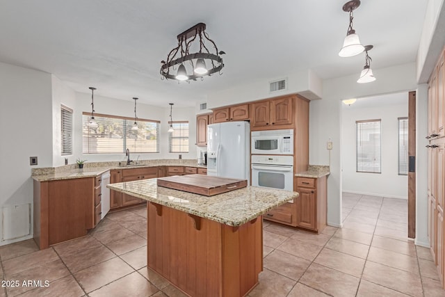 kitchen with sink, white appliances, light tile patterned floors, and a center island