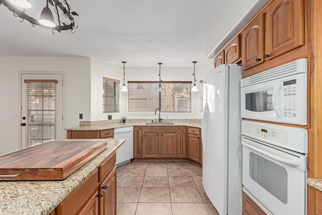 kitchen with sink, light stone counters, light tile patterned floors, pendant lighting, and white appliances