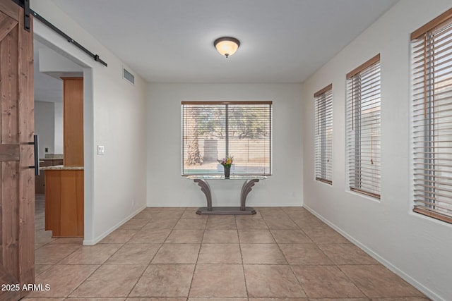 hall with a barn door and light tile patterned floors