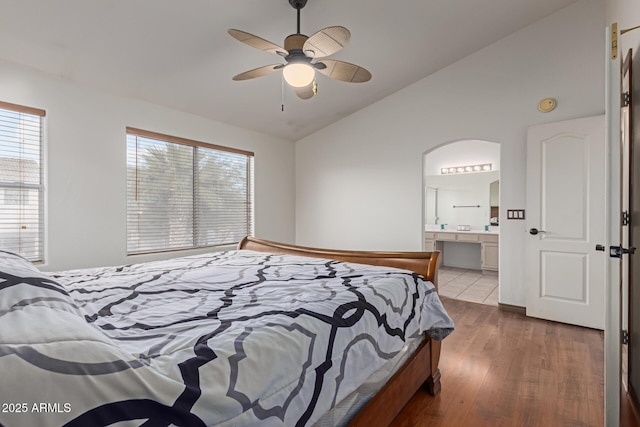 bedroom featuring lofted ceiling, ensuite bath, multiple windows, and light wood-type flooring