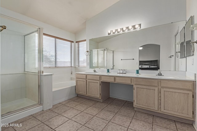 bathroom featuring tile patterned flooring, shower with separate bathtub, vaulted ceiling, and vanity