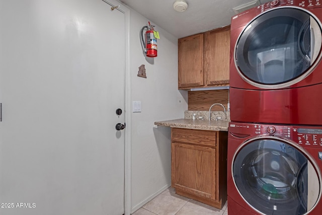 washroom with stacked washer / dryer, light tile patterned flooring, and cabinets