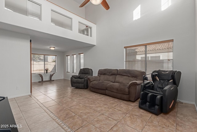 living room with light tile patterned floors, ceiling fan, and a high ceiling