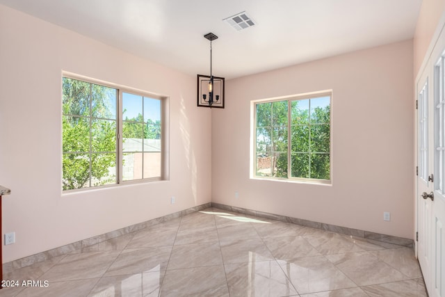 empty room featuring a notable chandelier and plenty of natural light