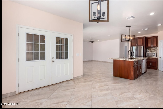 kitchen with pendant lighting, sink, a kitchen island with sink, stainless steel appliances, and ceiling fan with notable chandelier