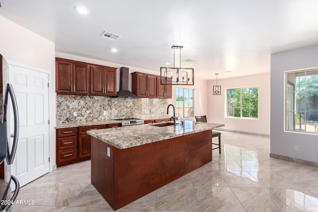 kitchen featuring a kitchen island with sink, wall chimney exhaust hood, plenty of natural light, and sink