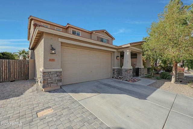 view of front of property with a garage, concrete driveway, stone siding, fence, and stucco siding