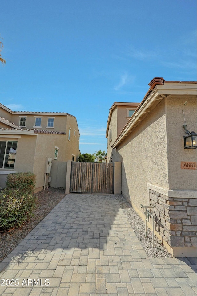 view of side of home featuring fence, a gate, and stucco siding