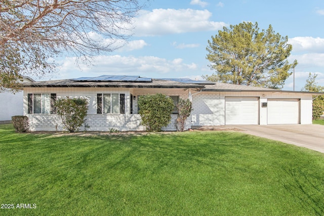 ranch-style home with a garage, a front yard, and solar panels