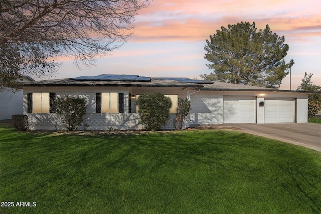 prairie-style house featuring a garage, a yard, and solar panels