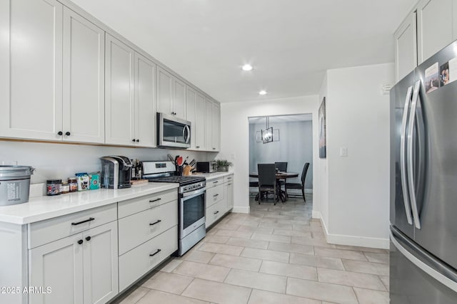 kitchen with stainless steel appliances, light tile patterned floors, white cabinets, and decorative light fixtures