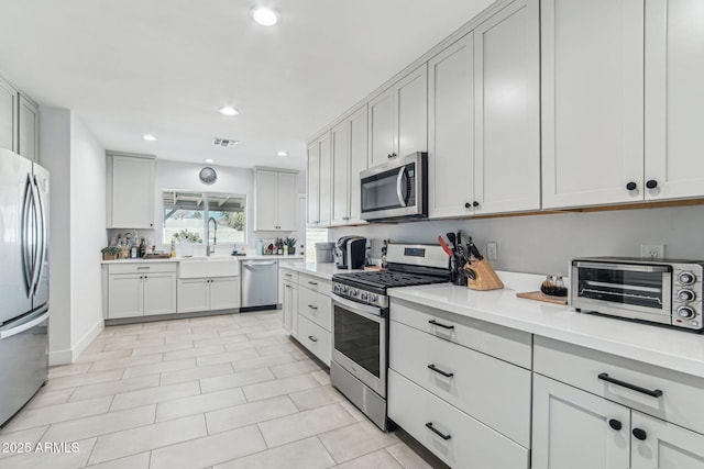 kitchen featuring stainless steel appliances, white cabinetry, and sink