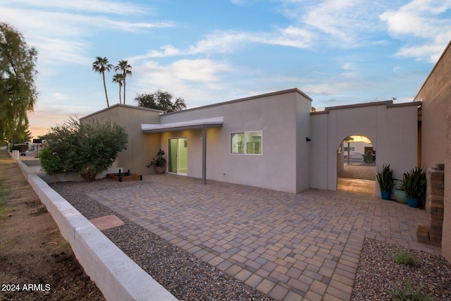 back house at dusk featuring a patio