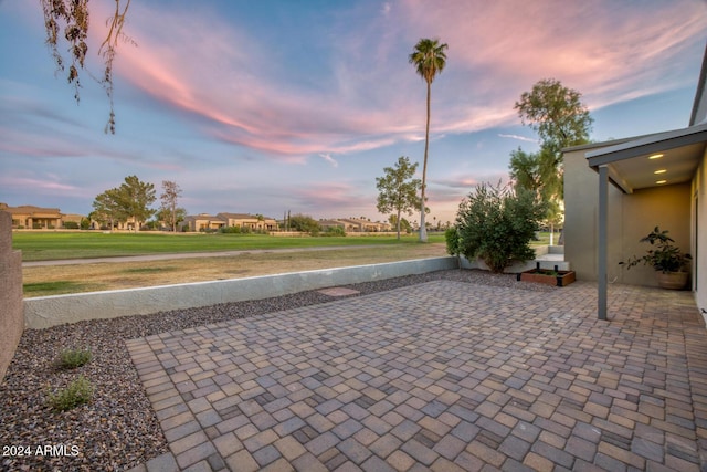 patio terrace at dusk featuring a yard