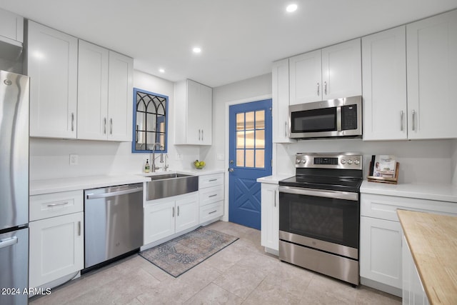 kitchen featuring white cabinets, appliances with stainless steel finishes, butcher block countertops, and sink