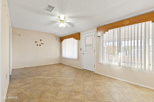 empty room featuring a textured ceiling, a wealth of natural light, and ceiling fan