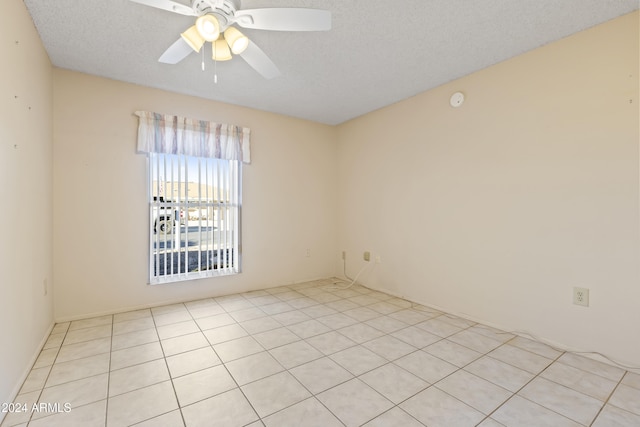 spare room featuring ceiling fan, light tile patterned flooring, and a textured ceiling