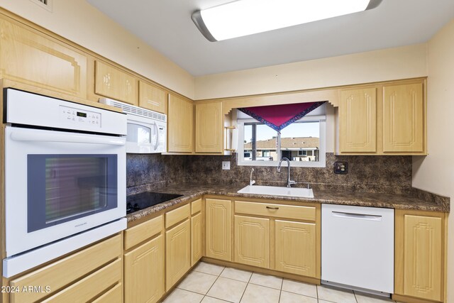 kitchen featuring light brown cabinetry, white appliances, backsplash, and sink