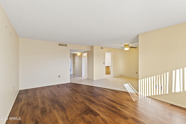 empty room with a textured ceiling, light hardwood / wood-style flooring, and ceiling fan