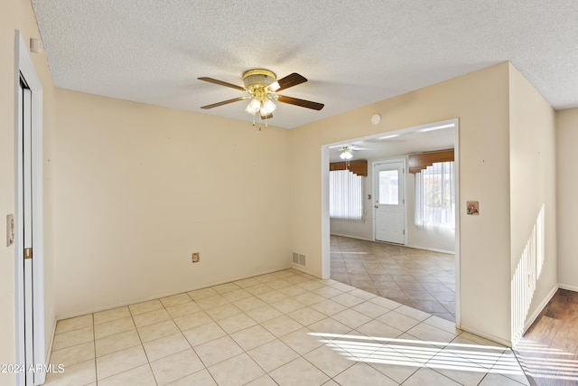 spare room with ceiling fan, light tile patterned floors, and a textured ceiling