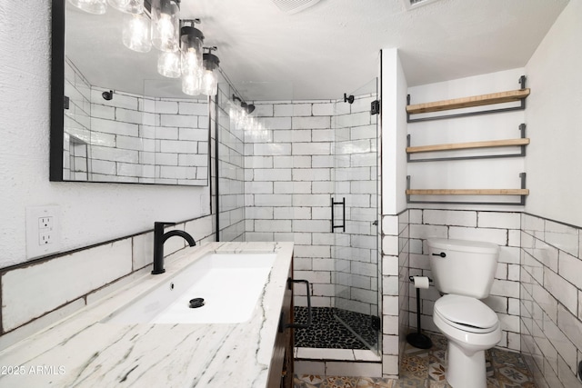 bathroom with vanity, toilet, an enclosed shower, and tile walls