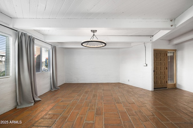 unfurnished room with beam ceiling