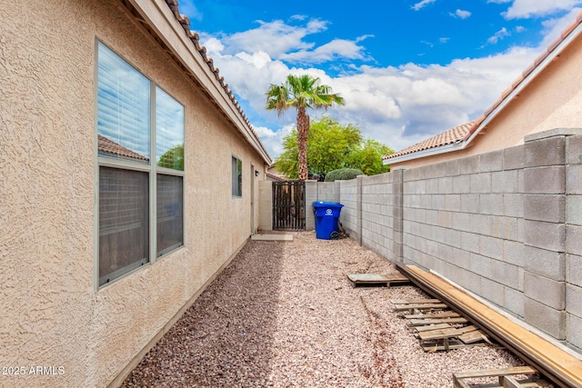 13359 W Post Dr, Surprise, AZ 85374 - view of side of home featuring stucco siding, a fenced backyard, and a gate