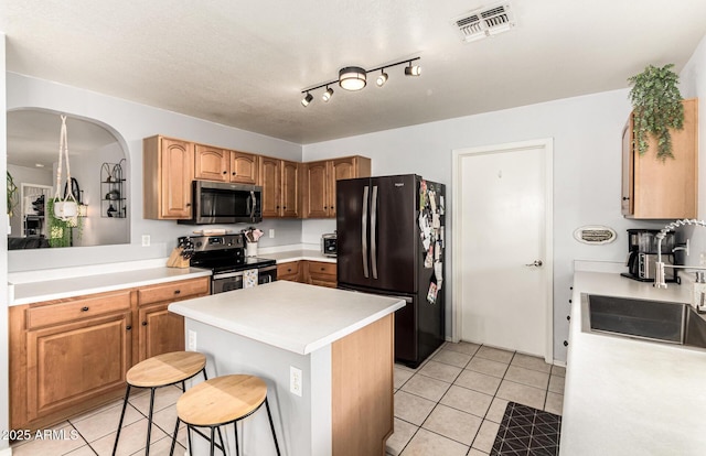 13359 W Post Dr, Surprise, AZ 85374 - kitchen featuring stainless steel appliances, arched walkways, light tile patterned flooring, a sink, and a kitchen bar