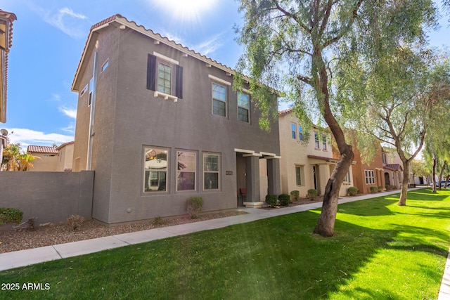 view of front of home featuring a front lawn, fence, a tile roof, and stucco siding