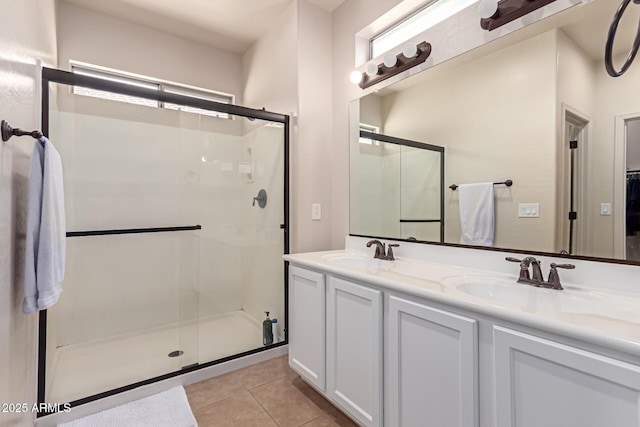 full bath featuring a sink, a shower stall, tile patterned floors, and double vanity