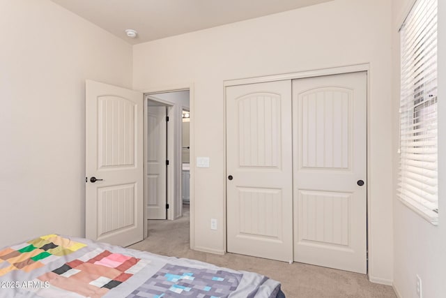 bedroom featuring light carpet, baseboards, and a closet