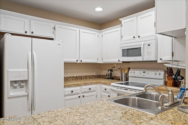 kitchen with a sink, white appliances, recessed lighting, white cabinetry, and light countertops