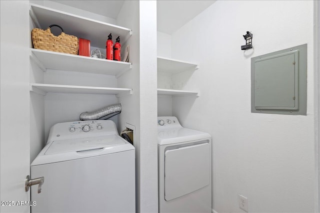 laundry room with electric panel, washing machine and clothes dryer, and laundry area
