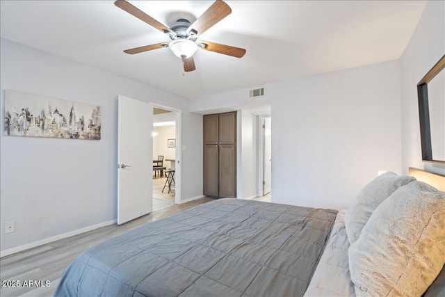 bedroom with baseboards, a ceiling fan, visible vents, and light wood-style floors