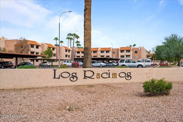 community sign with covered and uncovered parking and a residential view