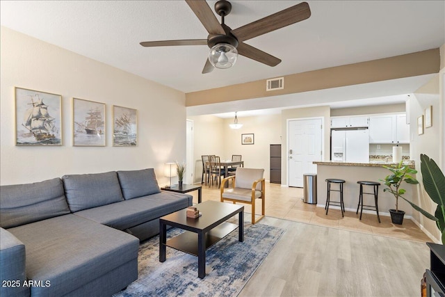 living area with a ceiling fan, visible vents, and light wood-style floors
