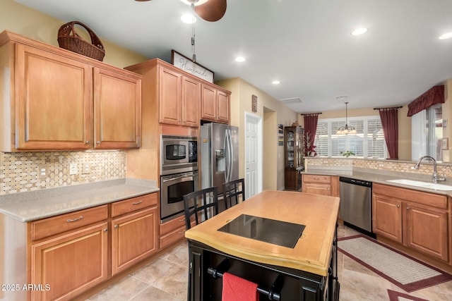 kitchen with hanging light fixtures, appliances with stainless steel finishes, sink, backsplash, and light tile patterned floors