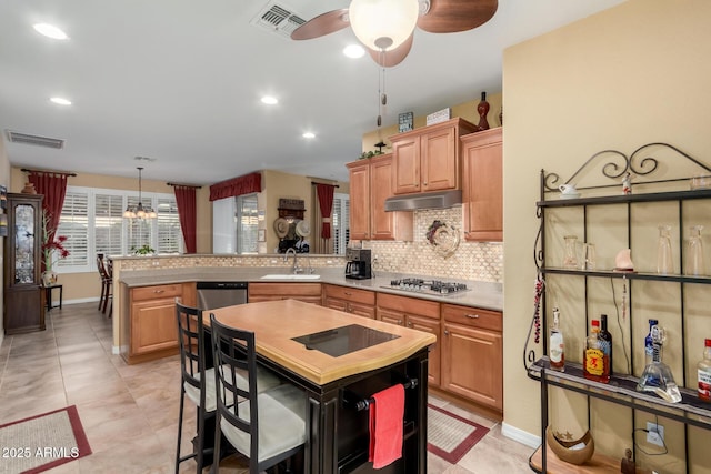 kitchen featuring pendant lighting, sink, ceiling fan with notable chandelier, decorative backsplash, and stainless steel appliances