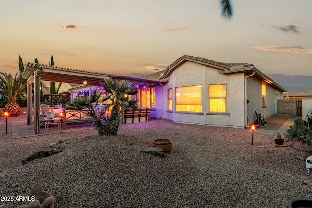 back house at dusk featuring a patio