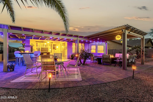 patio terrace at dusk with outdoor lounge area, exterior bar, and a pergola