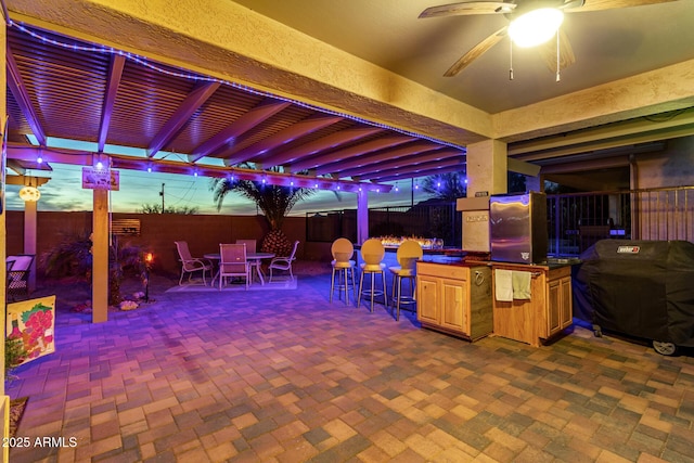 view of patio with ceiling fan, exterior bar, and a grill